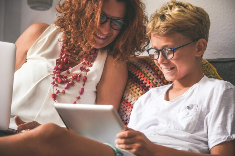 Un ado et sa maman qui regardent une tablette en souriant