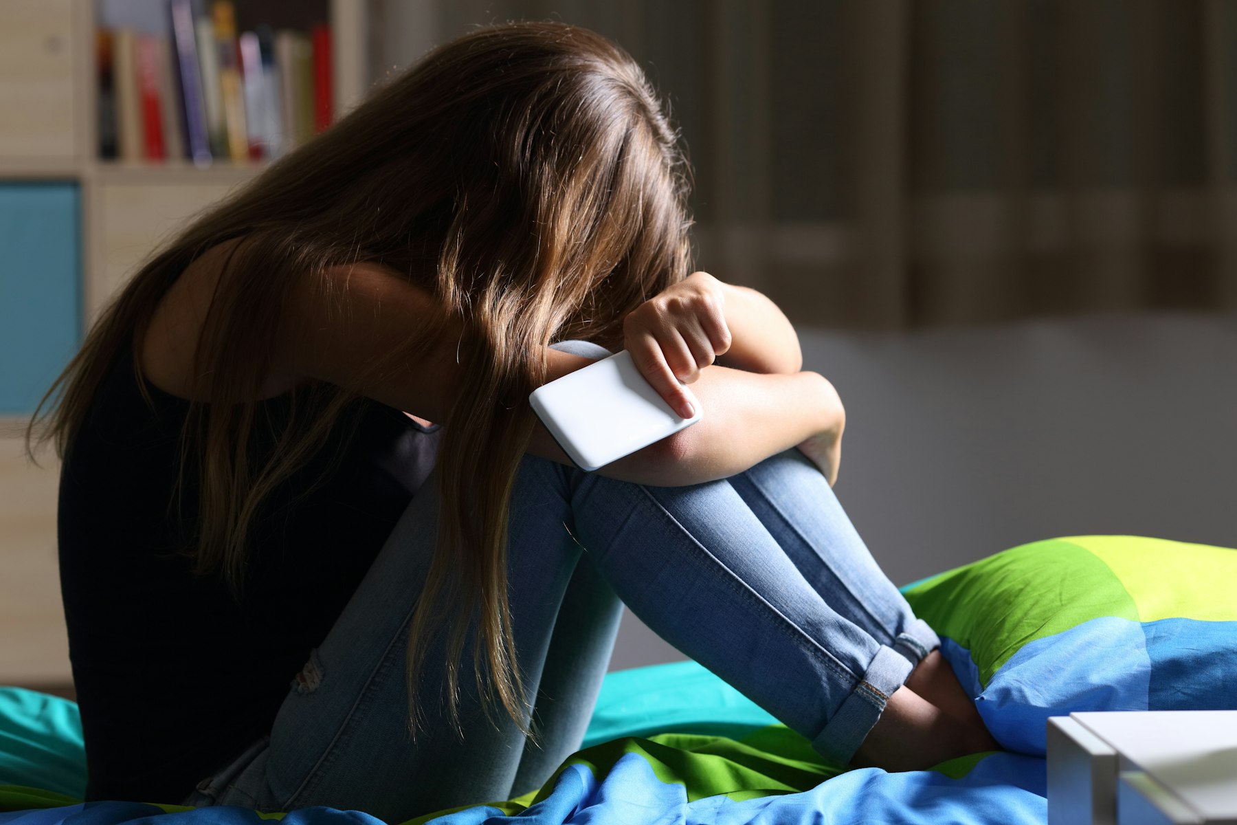 Image d'une jeune la tête enfouie dans ses jambes qui pleure